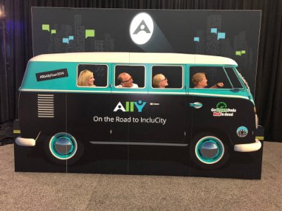 GVSU eLearning team in cardboard bus cut out with the Blackboard Ally logo